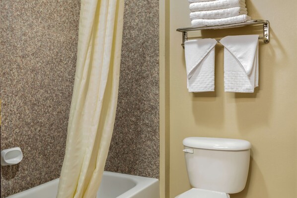 Une salle de bain avec un rideau de douche, des toilettes et un porte-serviettes avec des serviettes pliées.