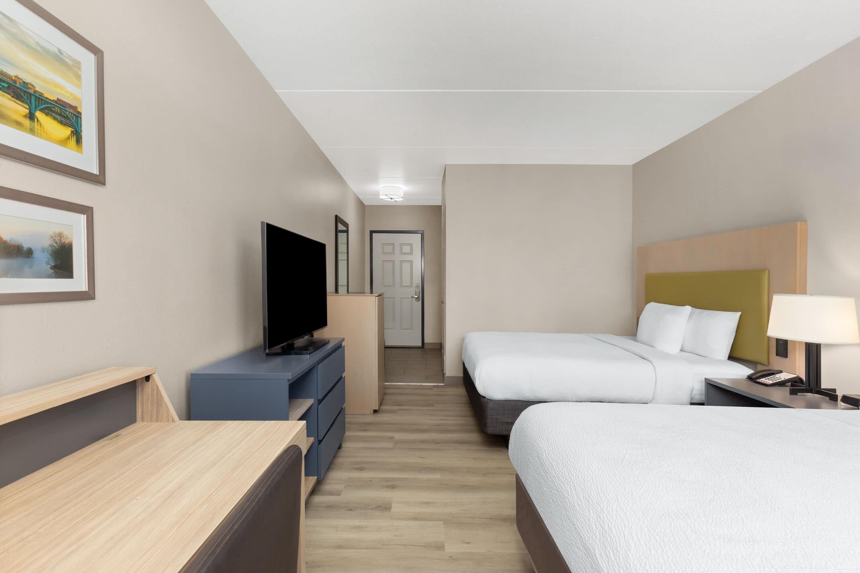 Une chambre d’hôtel avec un lit, une table de chevet, une lampe et un téléviseur posé sur une commode.