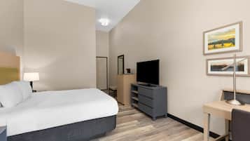 Una habitación de hotel con cama, escritorio, televisor y espejo.