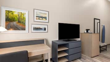 Habitación de hotel moderna con escritorio, televisor de pantalla plana, aparador y tres cuadros en la pared.