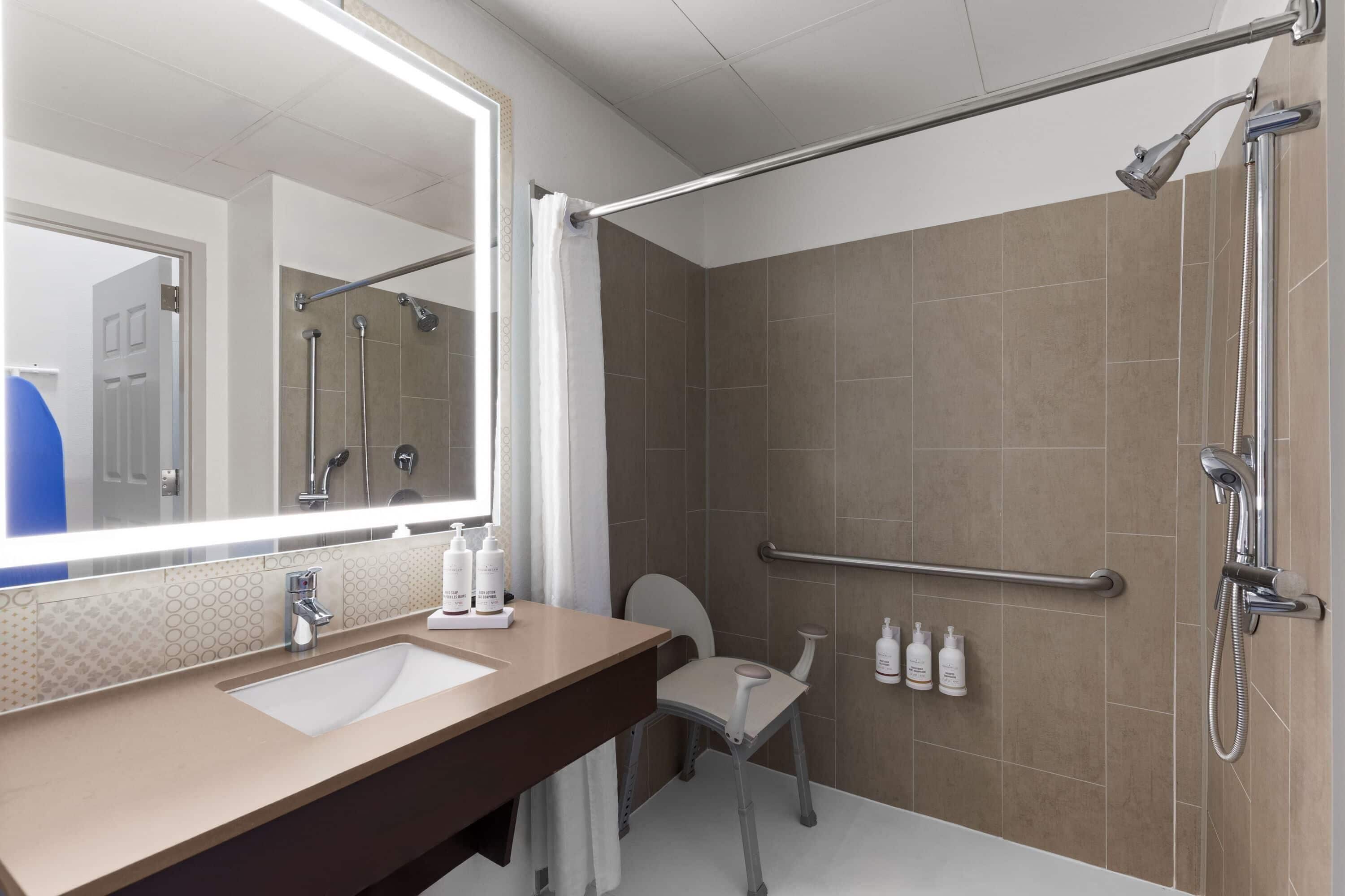 A modern bathroom with a large mirror, a sink, a toilet, and a shower area.