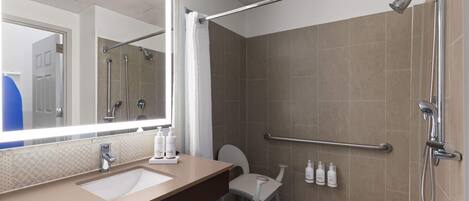 A modern bathroom with a large mirror, a sink, a toilet, and a shower area.