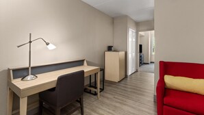 A modern, well-lit room with a desk, chair, and a red sofa. - La Quinta Inn & Suites by Wyndham Knoxville West (Knoxville)