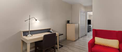 A compact room with a desk, chair, and a red sofa.