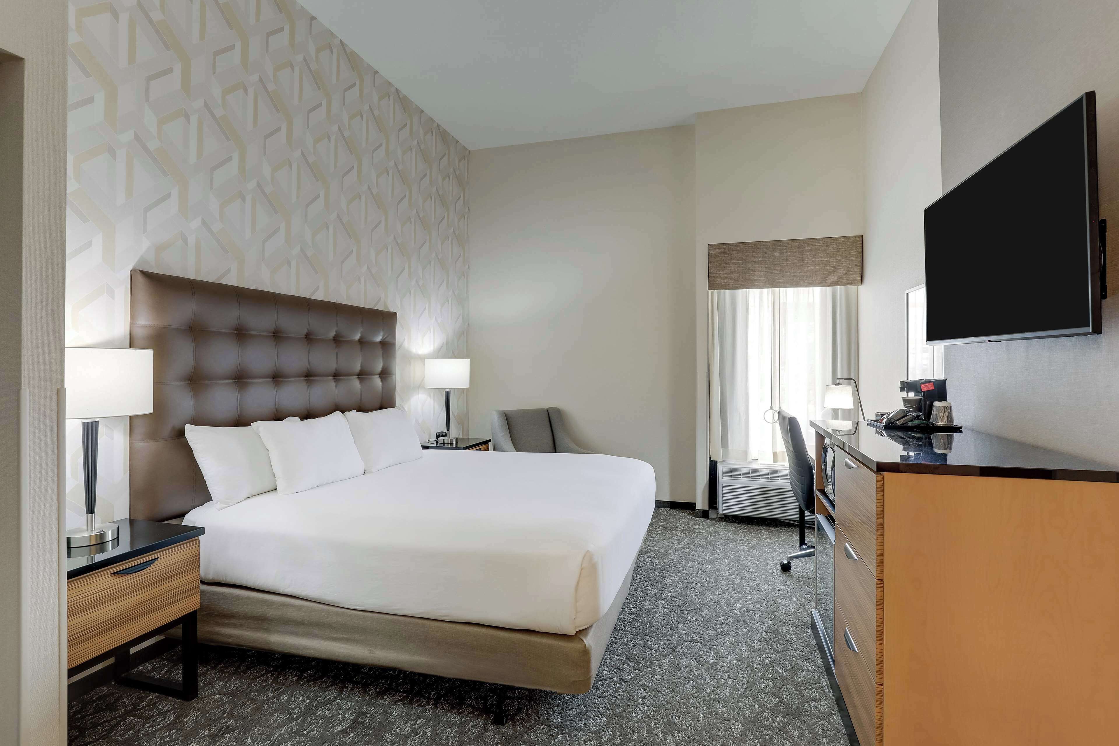 Une chambre d’hôtel avec un grand lit, un bureau, une chaise et un téléviseur.