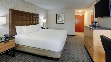 A hotel room with a large bed, bedside tables, a dresser, a flat-screen TV, and a framed picture on the wall.