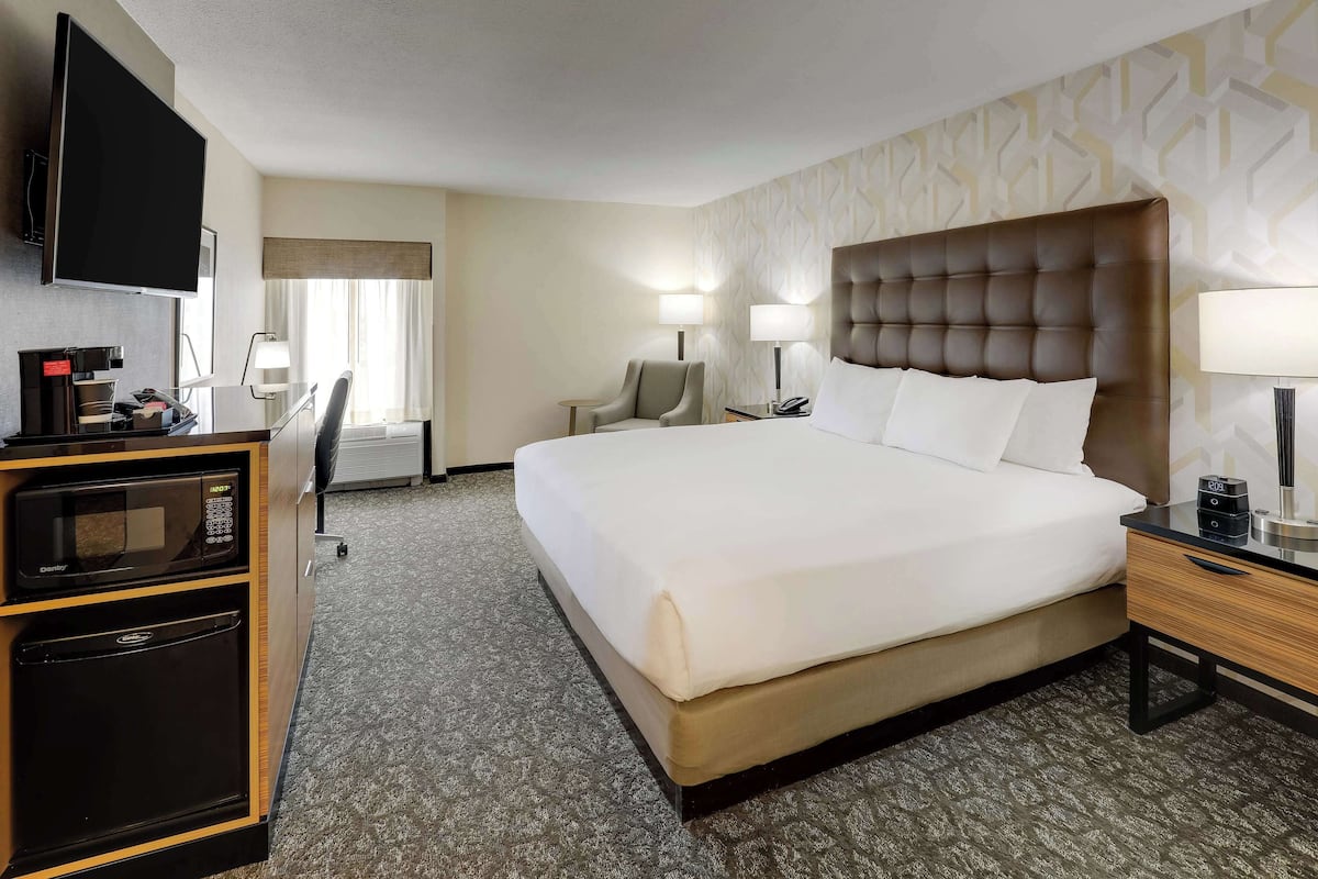 Habitación de hotel con una cama grande, un escritorio, un televisor de pantalla plana, microondas y cafetera.