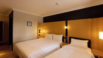 Una habitación de hotel con dos camas individuales, cabeceros de madera y lámparas de noche.