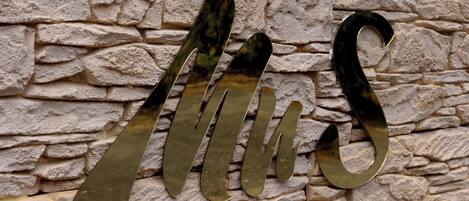 A metallic sign with the letters "MUS" mounted on a stone wall.