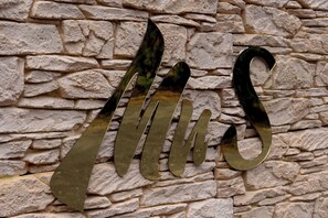 A metallic sign with the letters "MUS" mounted on a stone wall.