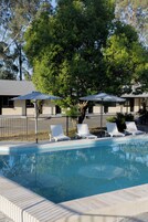 Una piscina al aire libre, sombrillas, sillones reclinables de piscina