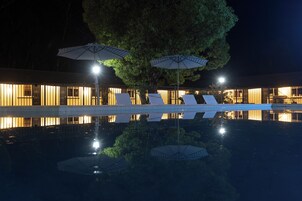 Una piscina al aire libre, sombrillas, sillones reclinables de piscina