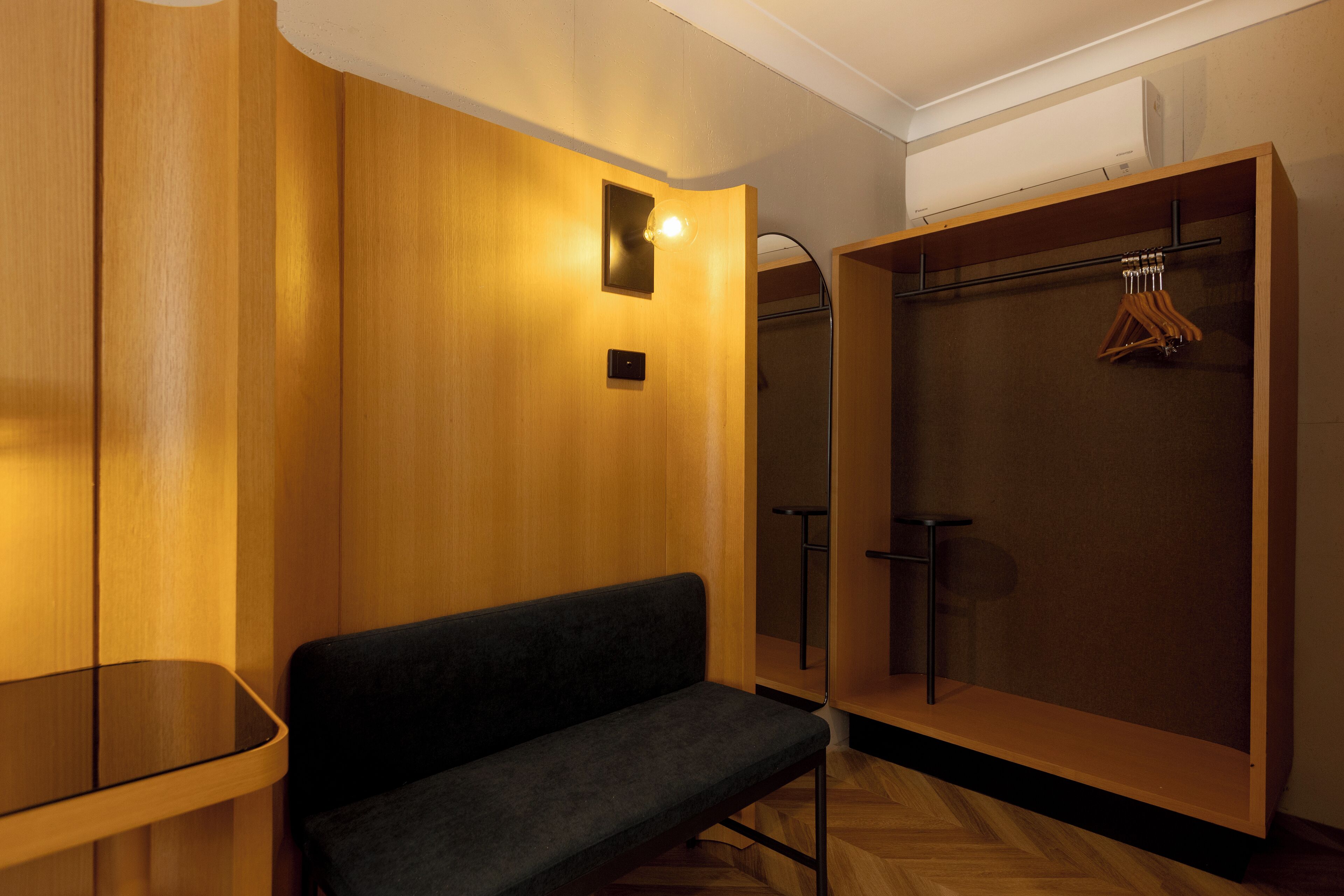 A modern, well-lit room with a wooden bench, a coat rack, and a built-in wardrobe.