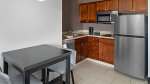 A compact kitchen with wooden cabinets, a stainless steel refrigerator, a microwave, and a coffee maker. - Residence Inn by Marriott Long Island Holtsville (Holtsville)
