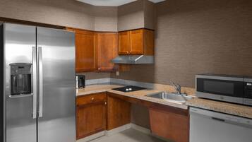 Una cocina moderna con electrodomésticos de acero inoxidable, armarios de madera y encimeras de granito, además de un microondas integrado.