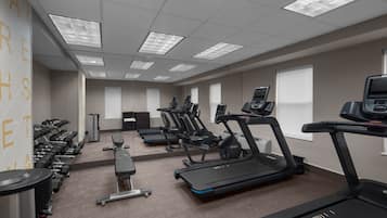 A gym with treadmills, dumbbells, and exercise equipment.