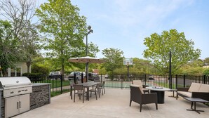 An outdoor patio with a grill, dining table, chairs, and a basketball hoop. - Residence Inn by Marriott Long Island Holtsville (Holtsville)