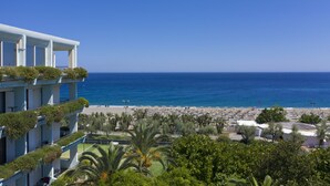 A hotel with balconies, a beach view, and a pool area.