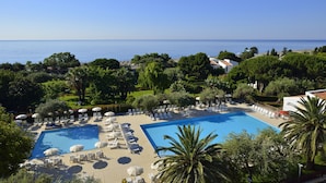 A resort with a large pool, sun loungers, and a view of the sea.