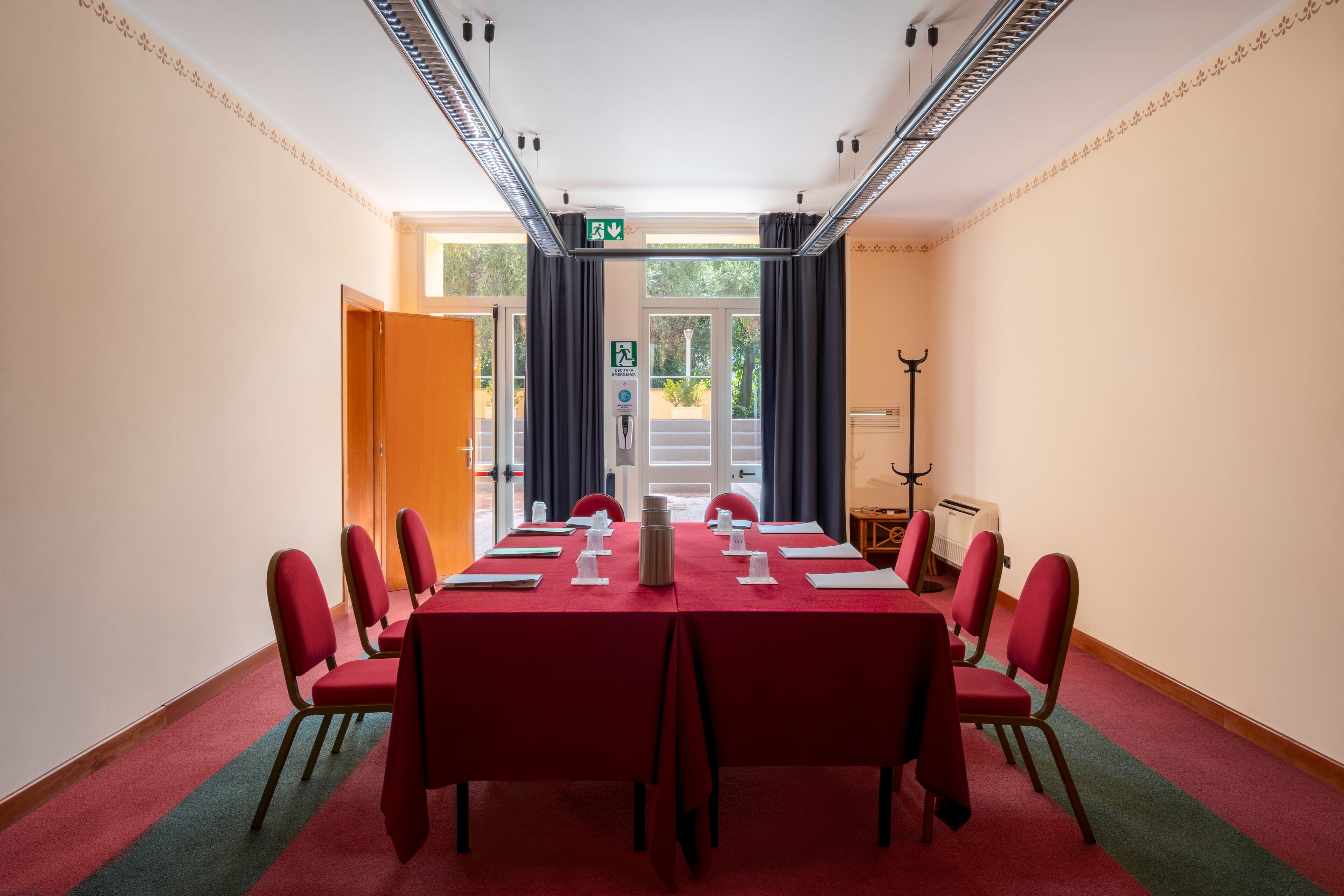 A conference room with a long table, red chairs, and a red carpet.