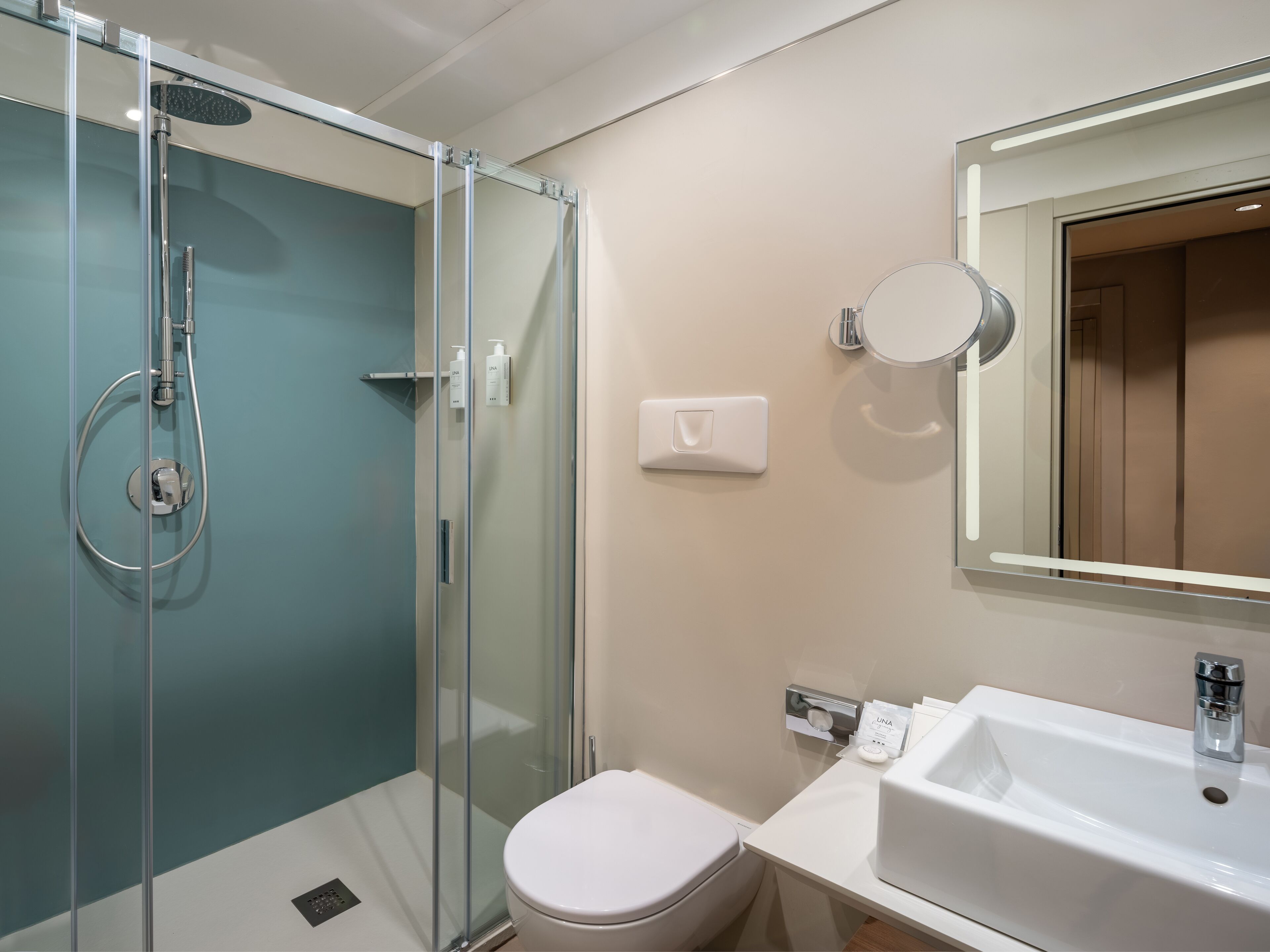 A modern bathroom with a glass-enclosed shower, a white toilet, and a sink with a mirror above it.