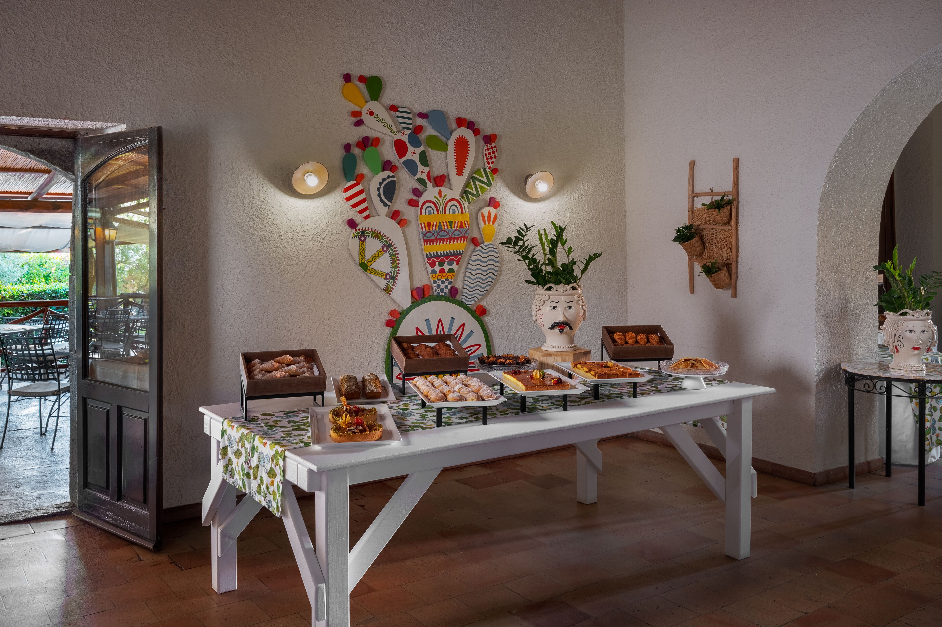 A buffet table with various food items, a decorative wall piece, and a potted plant.