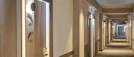 A hotel hallway with doors numbered 410 and 411, carpeted floors, and a long corridor with doors on both sides.