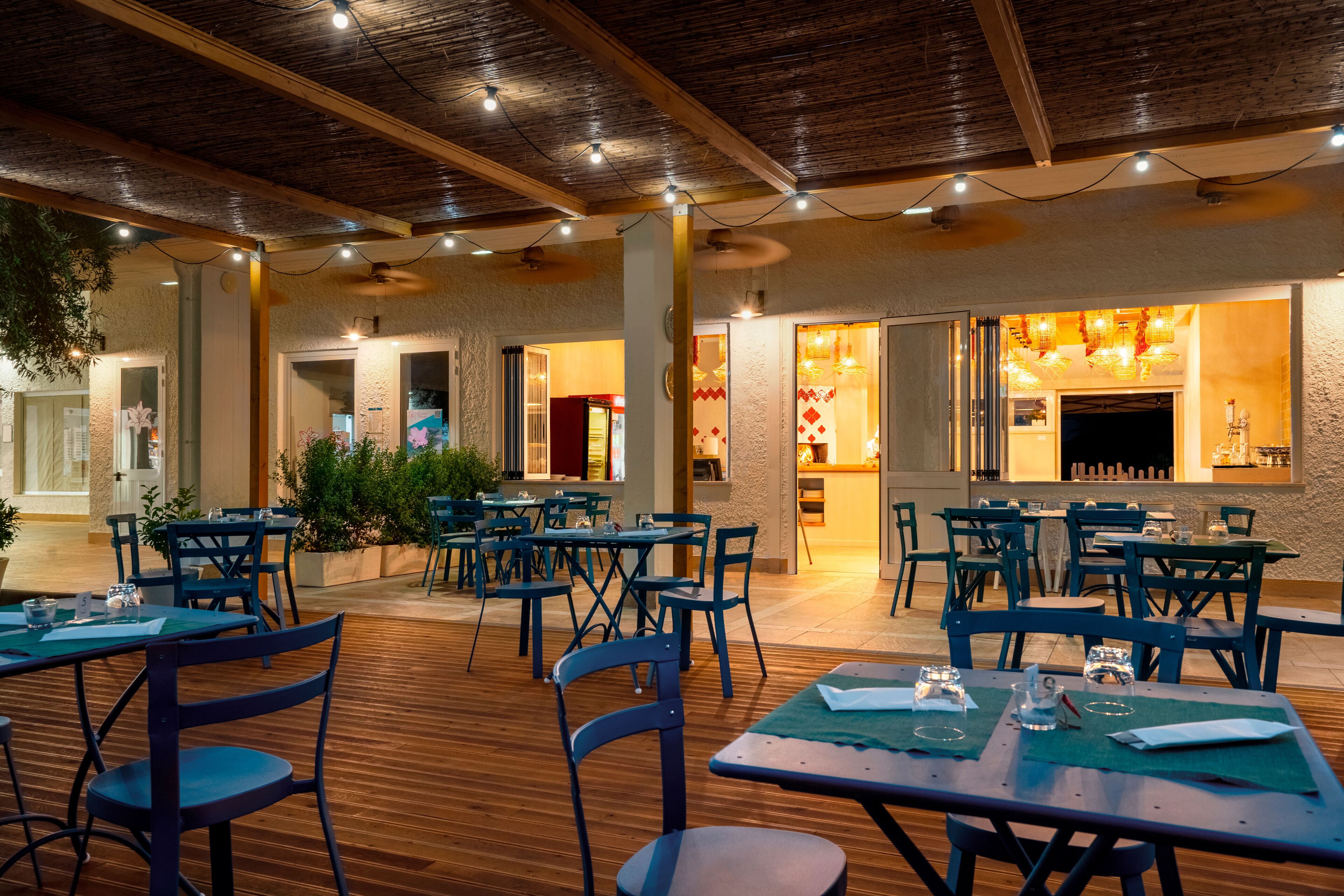A restaurant with wooden flooring, blue chairs, and tables set for dining.