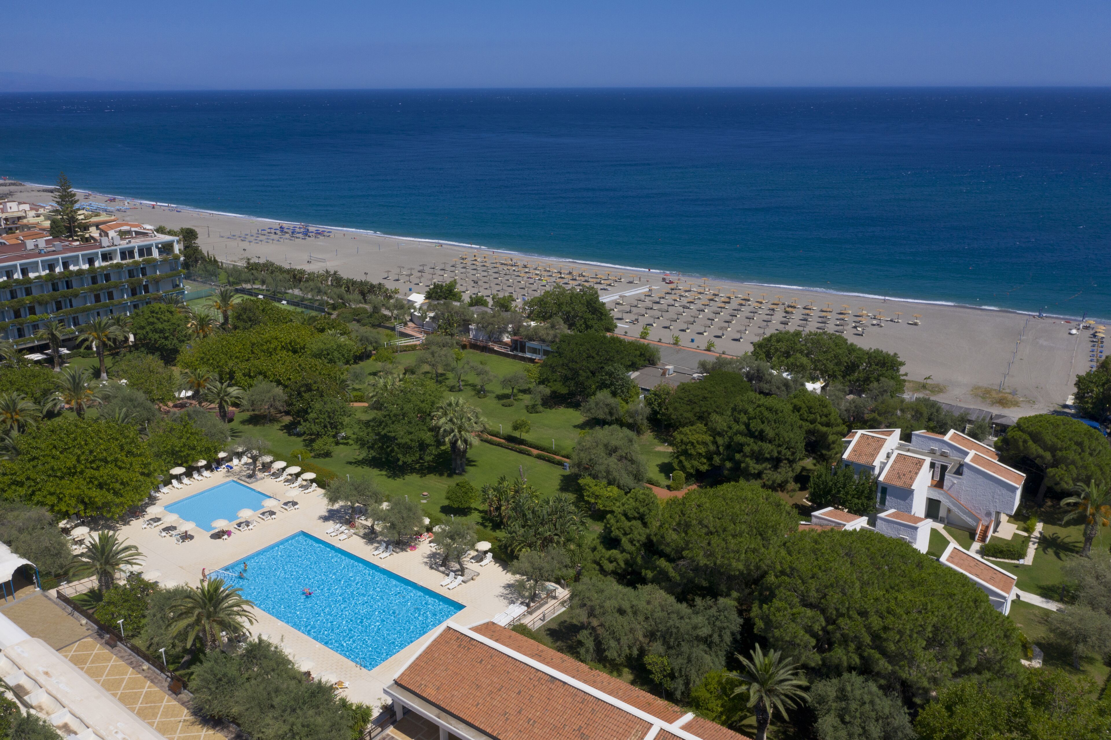 A resort with a large pool, beach area, and ocean view.