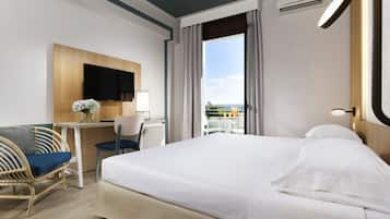 Una habitación de hotel con cama, escritorio, silla, televisión y vista al exterior.