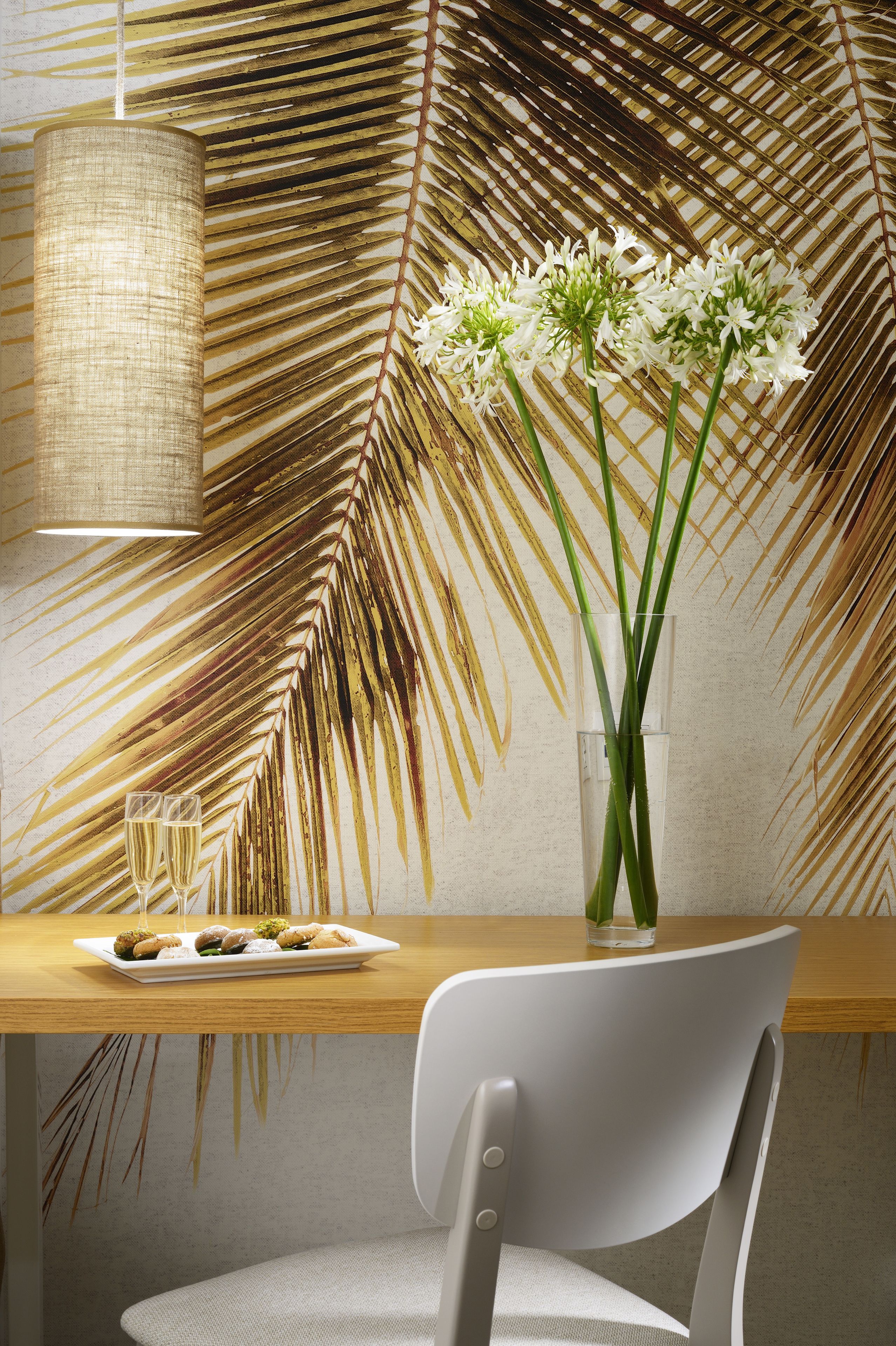 Un coin repas avec une table en bois, une chaise blanche et un vase contenant des fleurs blanches.