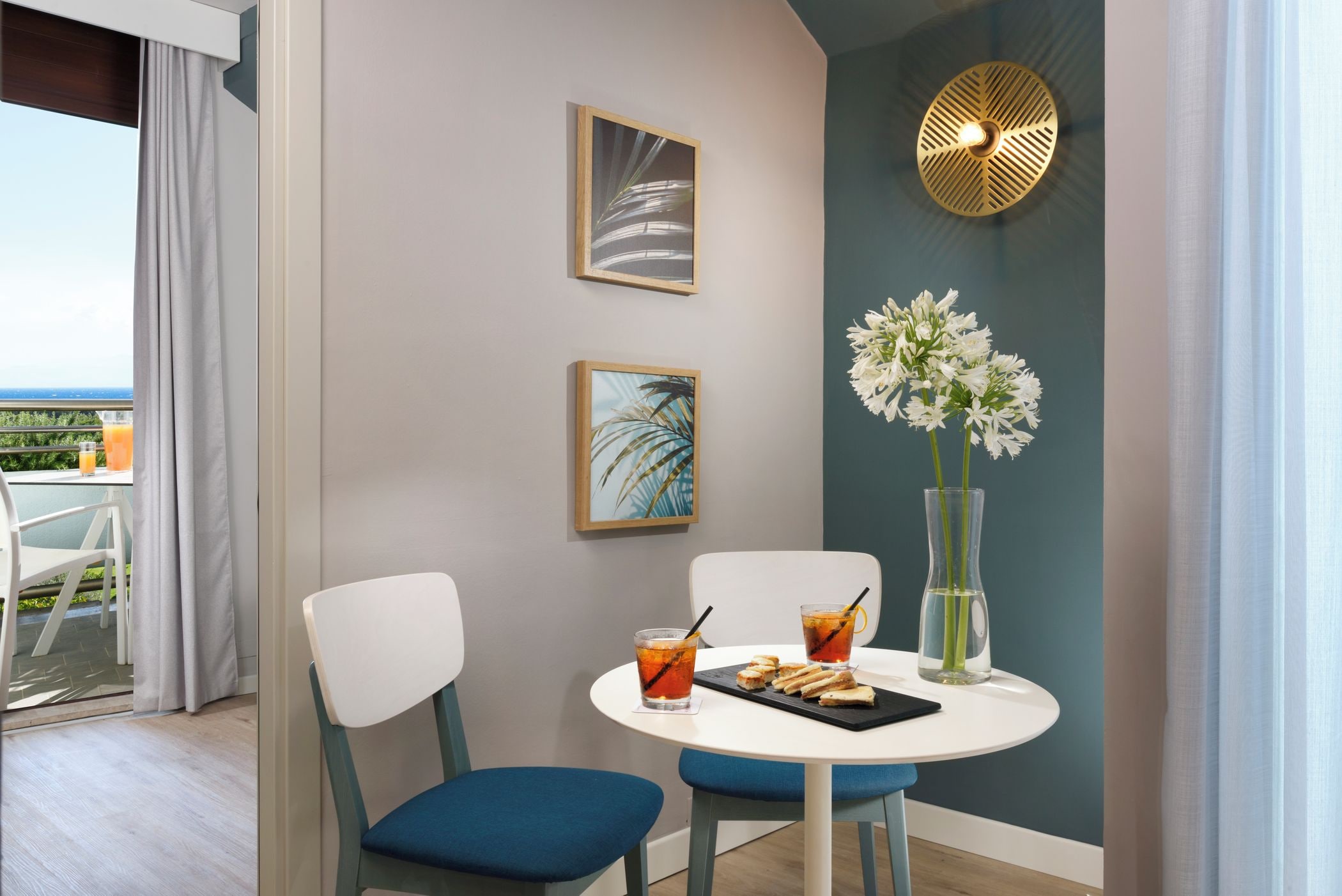 A dining area with a table, chairs, a vase with flowers, and artwork on the wall.