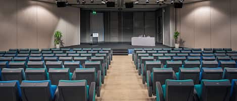 A conference room with rows of chairs, a stage, and a podium.