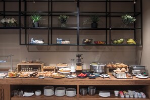 Montaje de bufé con diversos alimentos, platos y utensilios para servir.