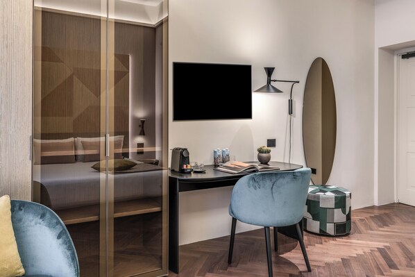 Habitación de hotel moderna con una cama, un escritorio con computadora, una silla, una tabla de surf y una planta pequeña.