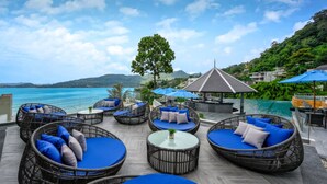 Un área de lounge en la azotea con mobiliario de mimbre y vistas al mar.