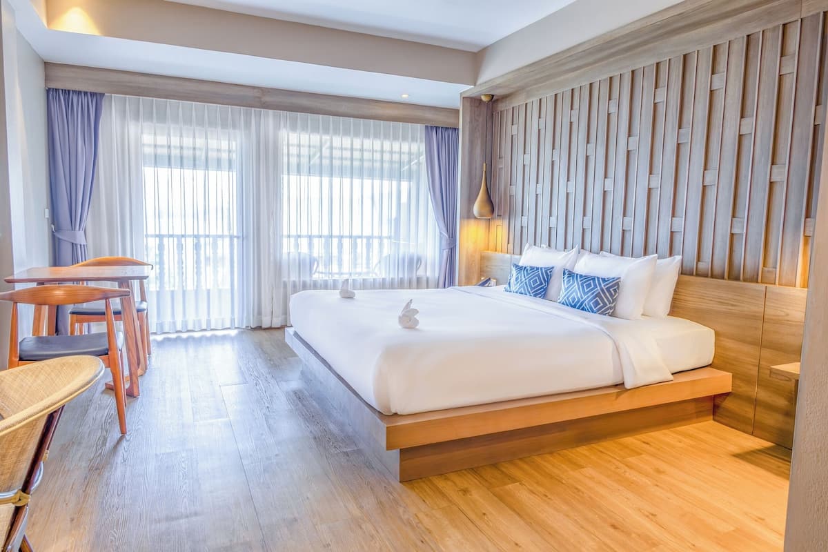 A modern hotel room with a wooden bed, a desk, and chairs.