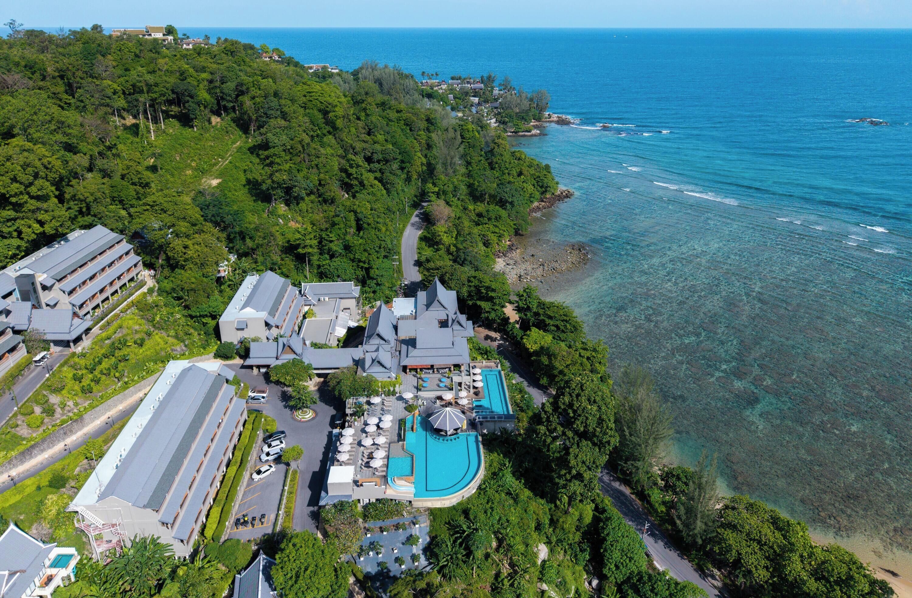 Vista aérea de un complejo turístico con varias construcciones, una piscina y acceso a la playa.