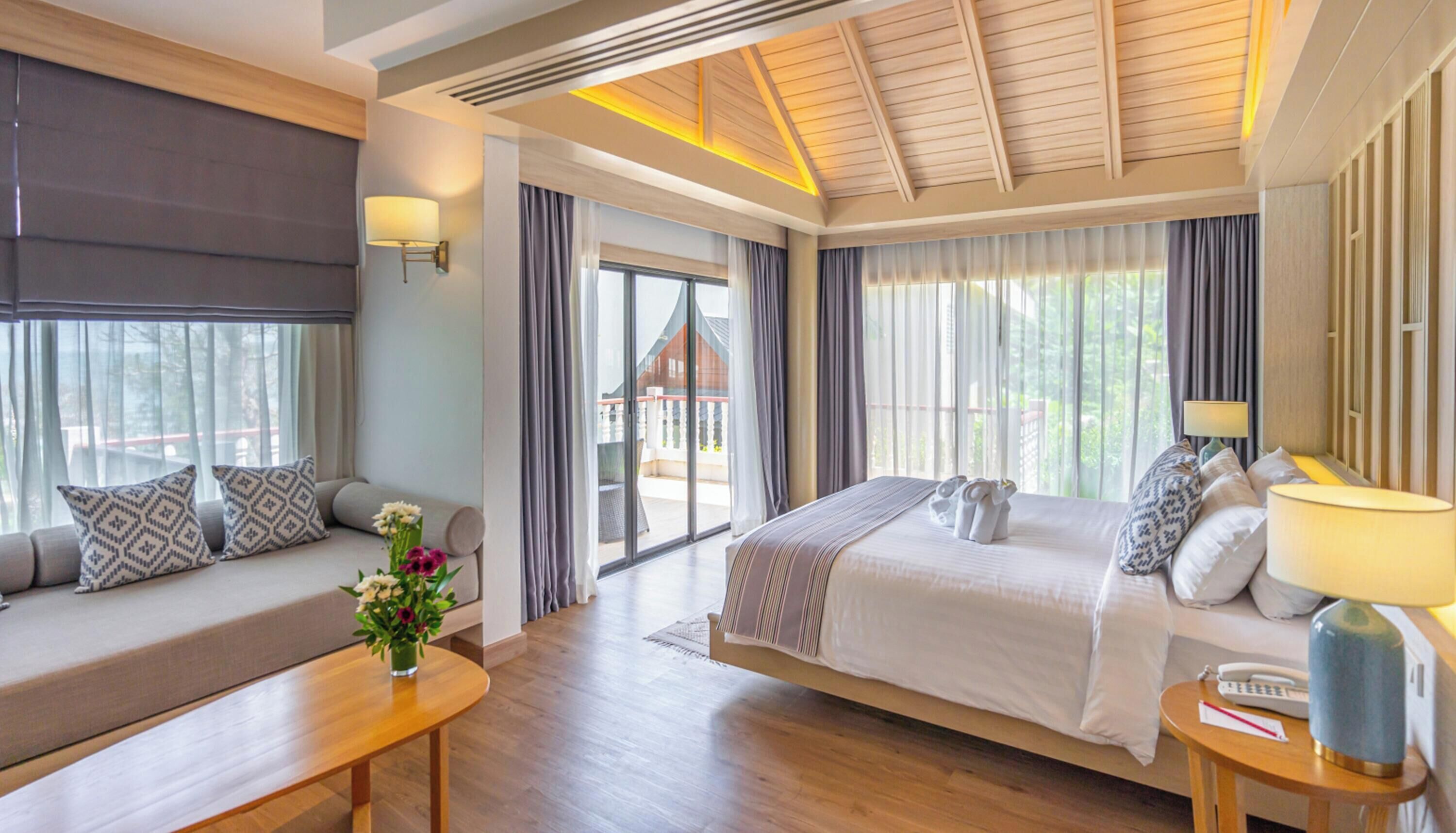 Habitación de hotel con cama, sofá, mesa y vistas al exterior.