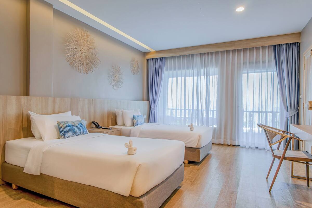 A hotel room with two beds, a desk, and a chair.