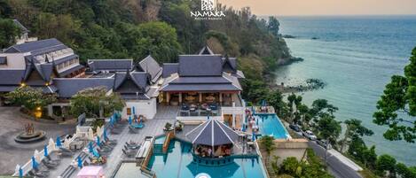 A resort with a swimming pool, lounge areas, and a view of the sea.