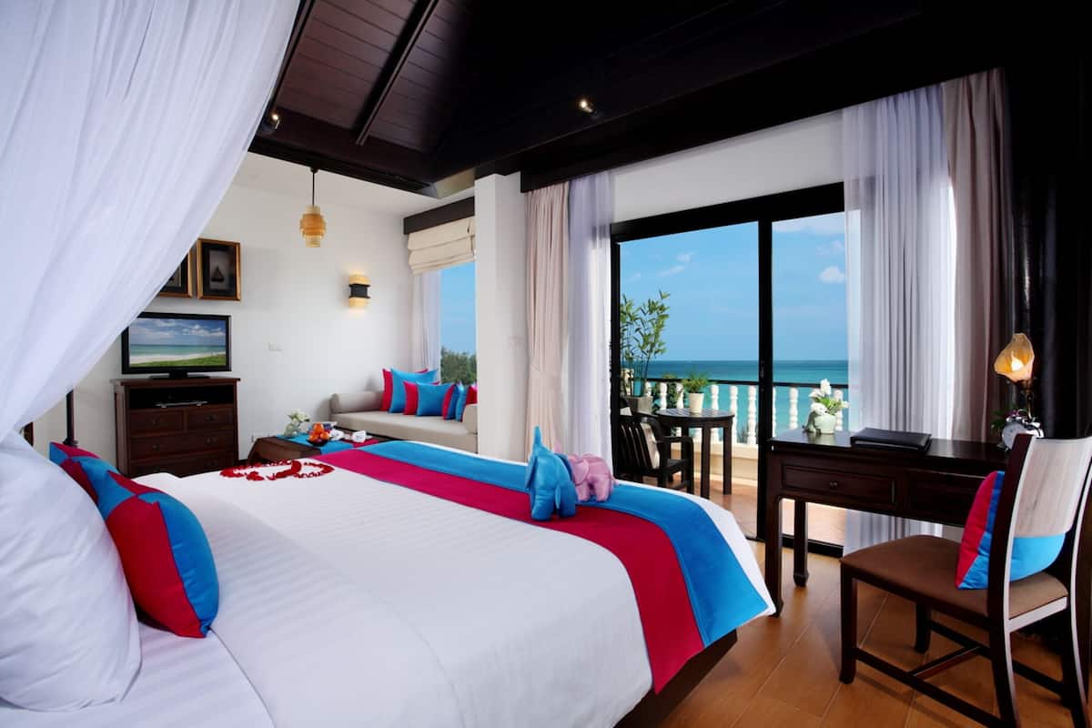 A hotel room with a large bed, a desk, and a view of the ocean.