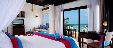 A hotel room with a large bed, a desk, and a view of the ocean.