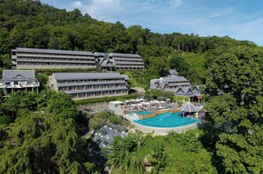 A resort with multiple buildings, a swimming pool, and lush greenery.