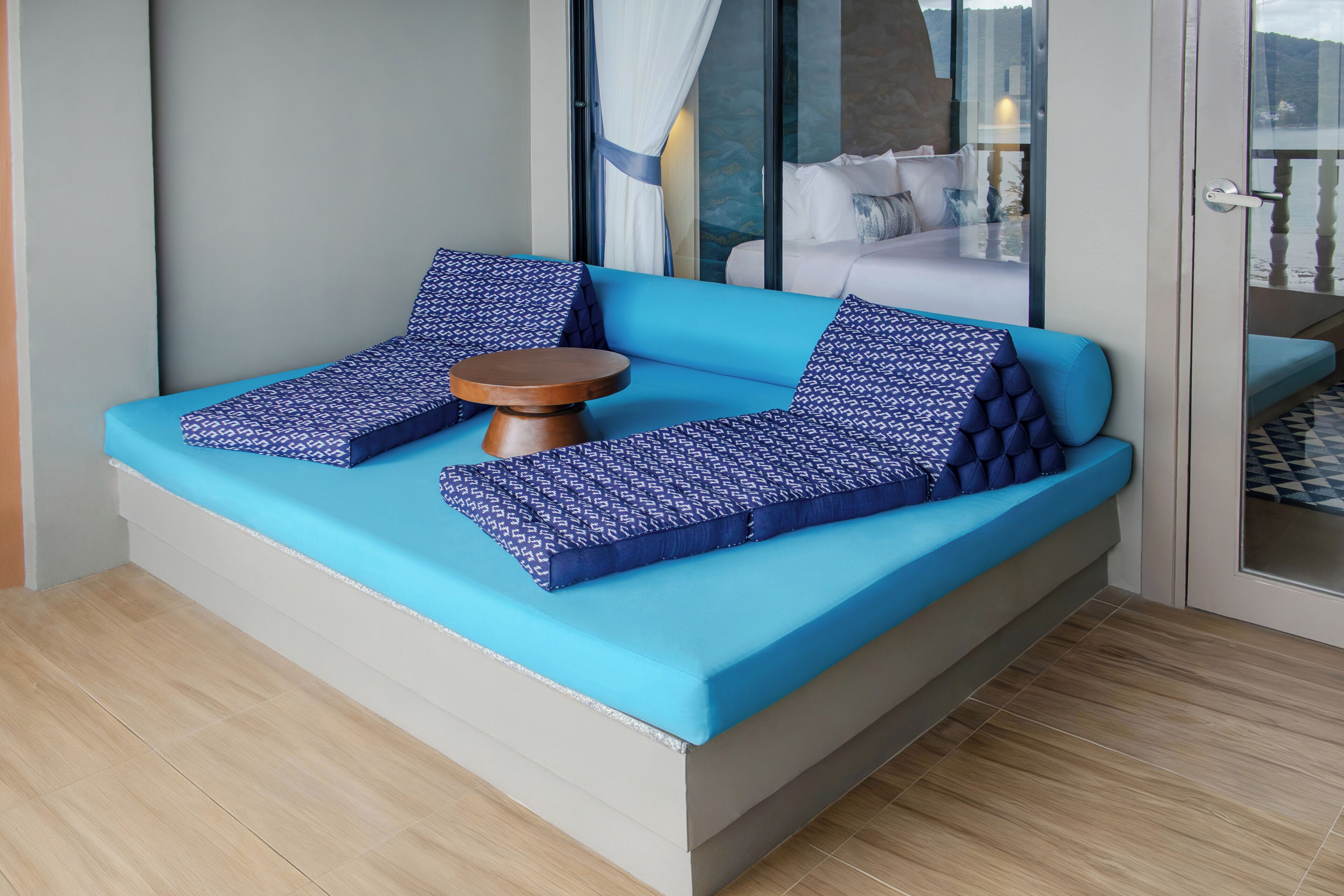 Una camera moderna con un divano blu, cuscini decorati e un tavolino in legno.