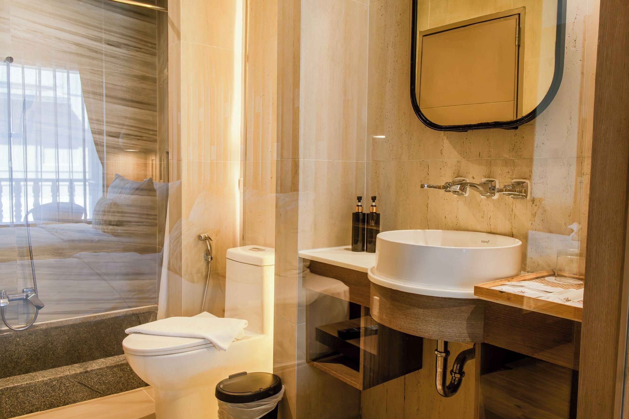 Un bagno moderno con cabina doccia in vetro, lavandino bianco e mobile contenitore in legno.