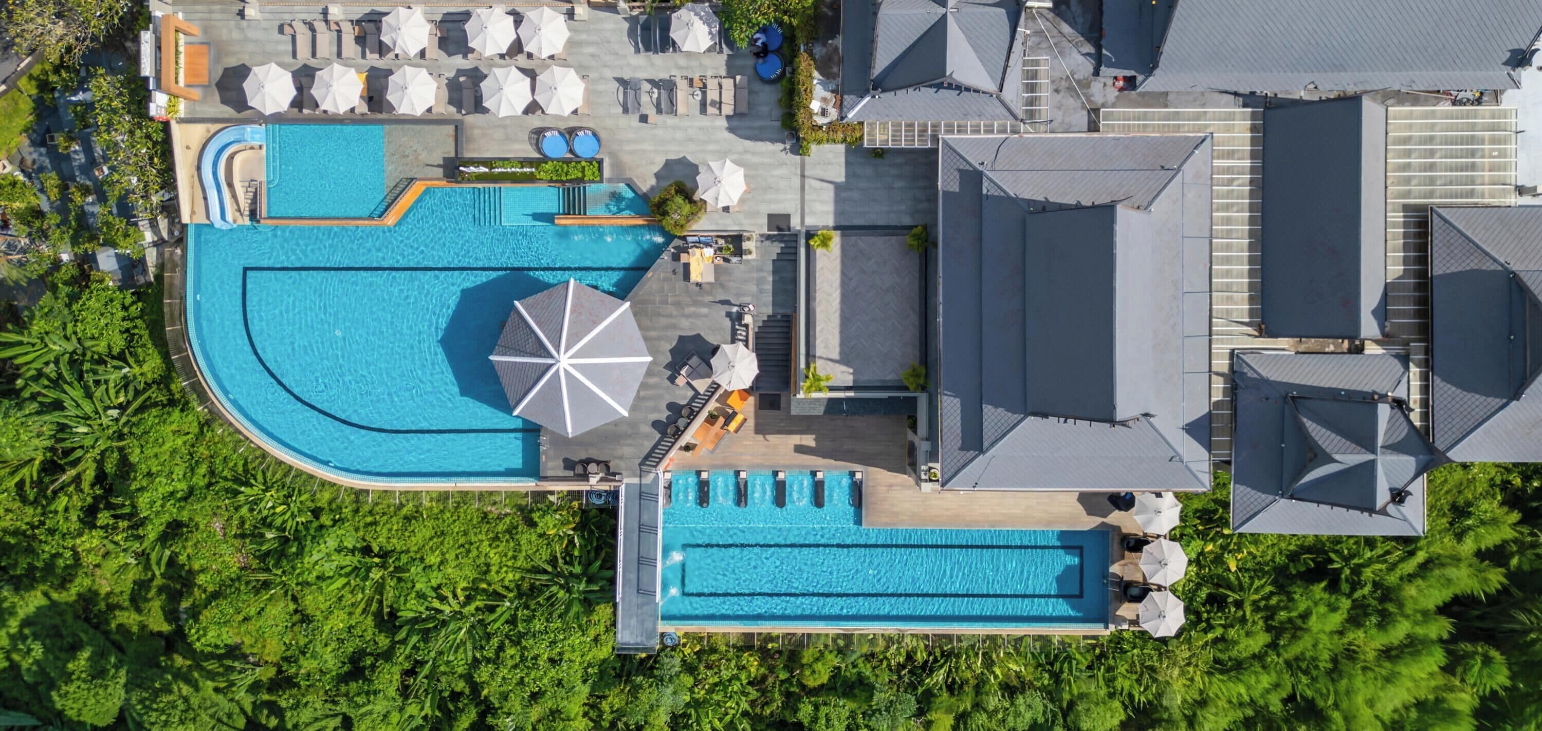 An aerial view of a resort with multiple swimming pools, sun loungers, and umbrellas.