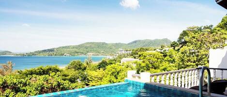 A swimming pool with a view of the sea and hills.