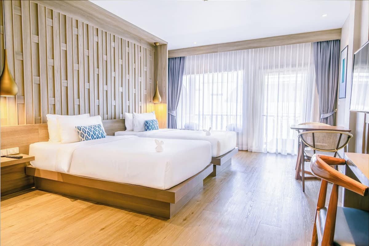 A modern hotel room with a large bed, a desk, and a chair.