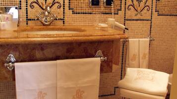 A bathroom with a tiled floor, a sink with a mirror above it, and a toilet with a towel hanging on the wall.